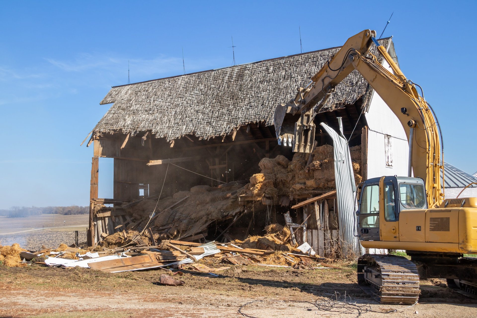 Excavator demolishing an old barn